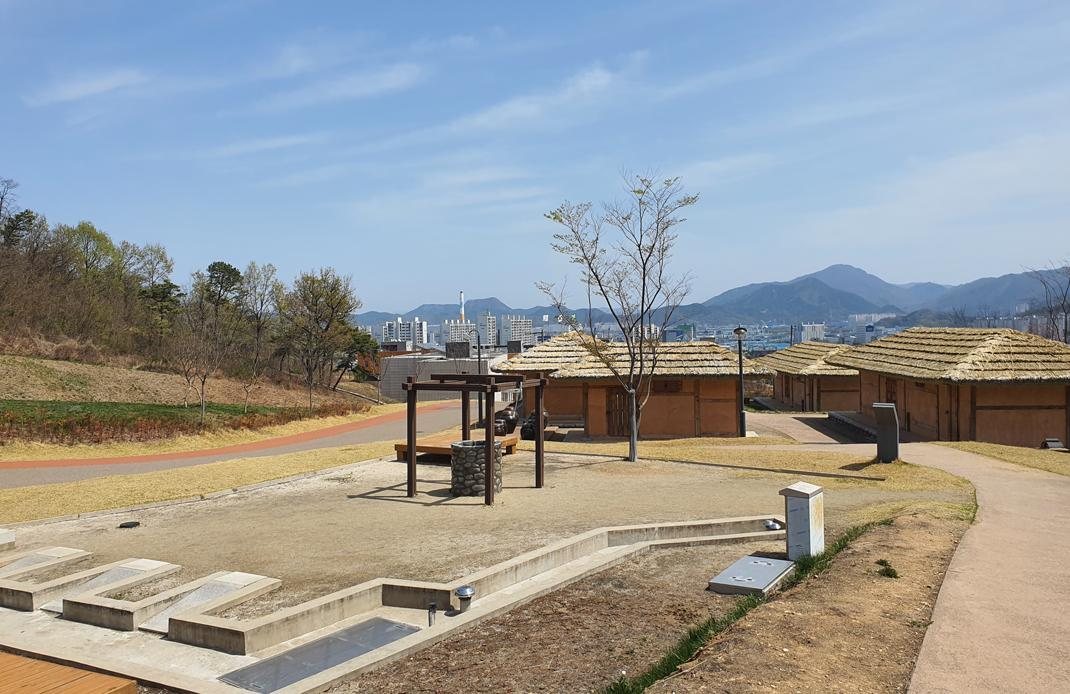 테마촌 — 야외의 초가 건물들, 뒤로 구미 시내와 산